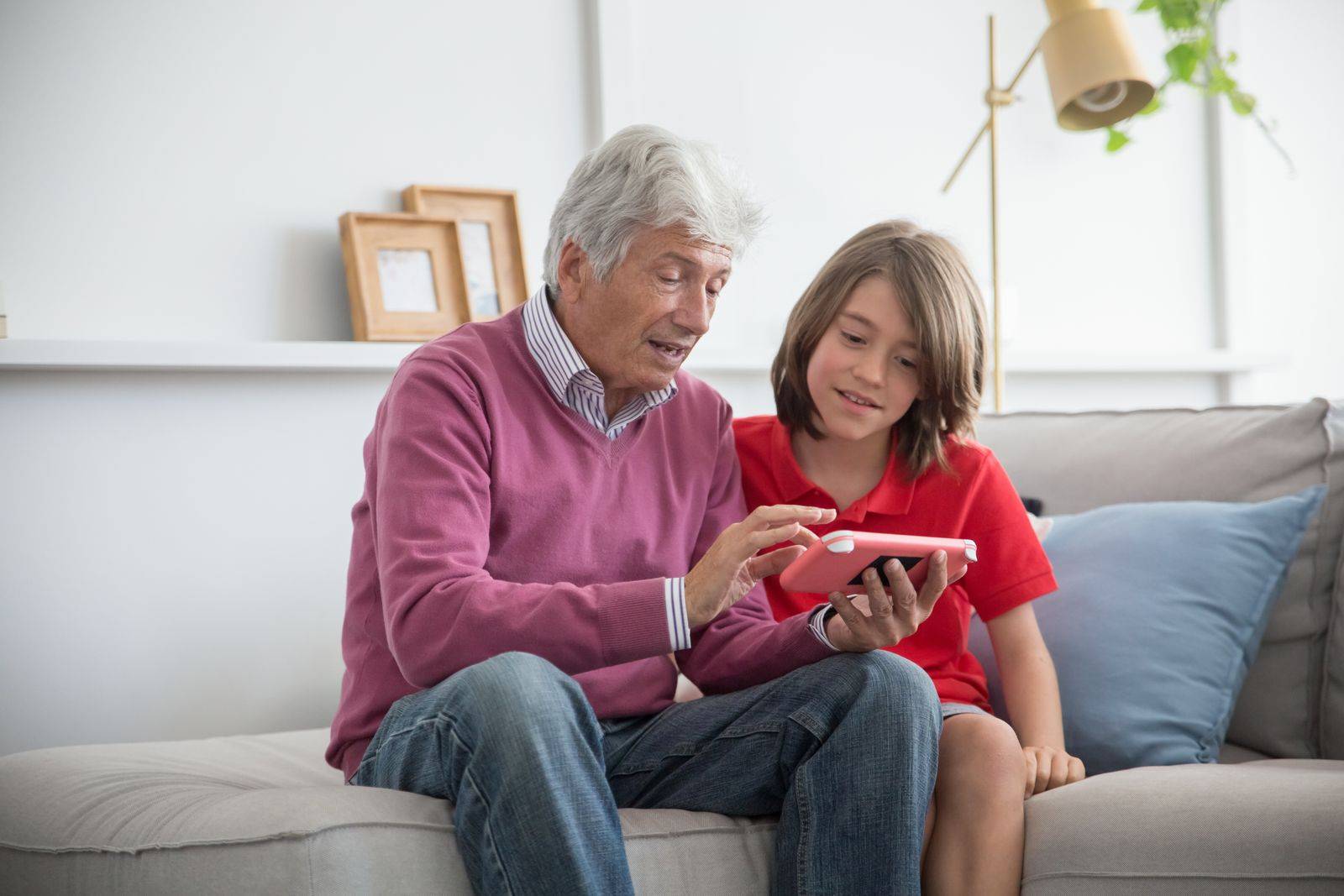 Un grand-père montre l'écran de son smartphone à une enfant assise à côté de lui.